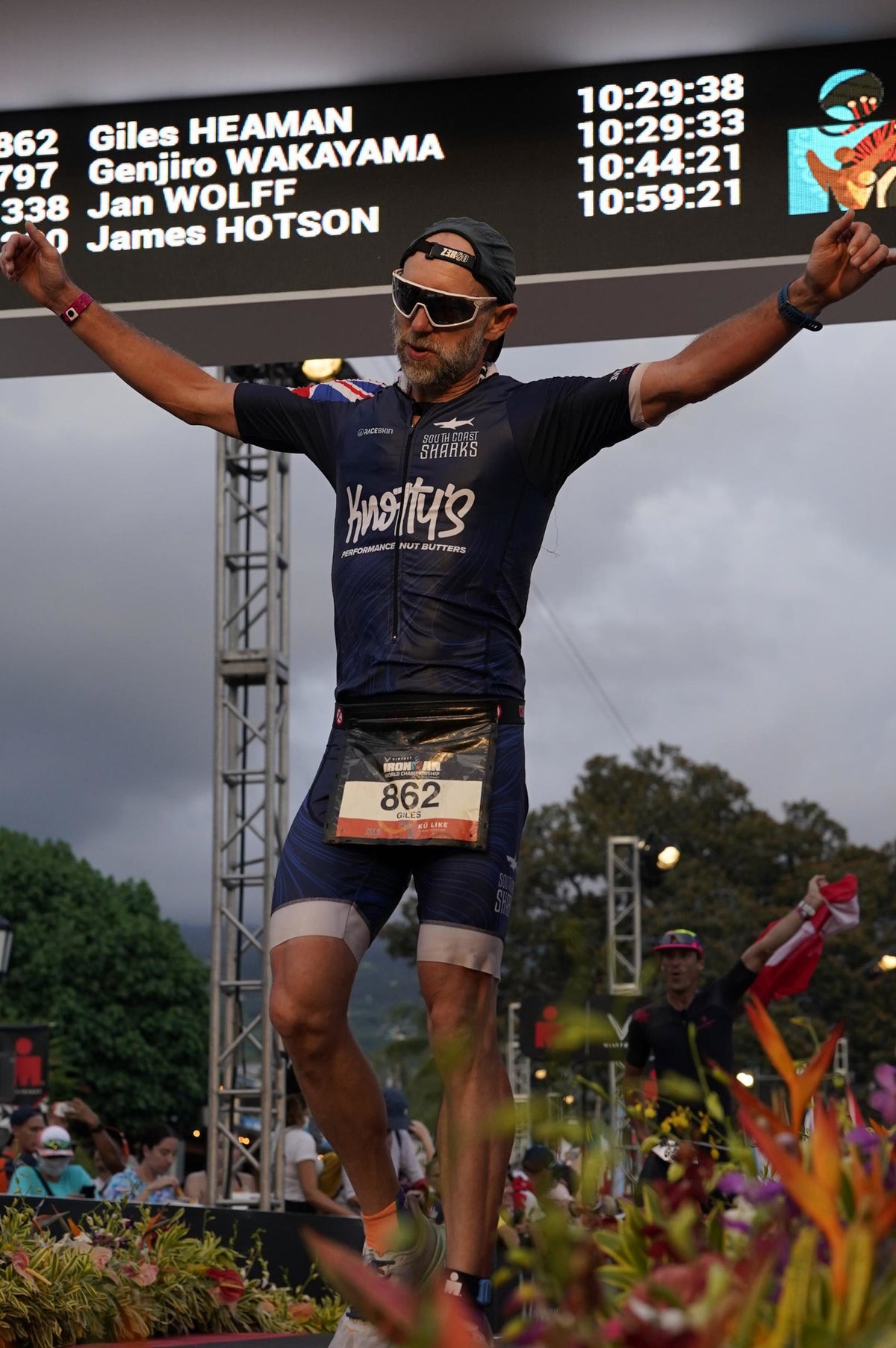 Male triathlete celebrating a finish line victory with arms raised.