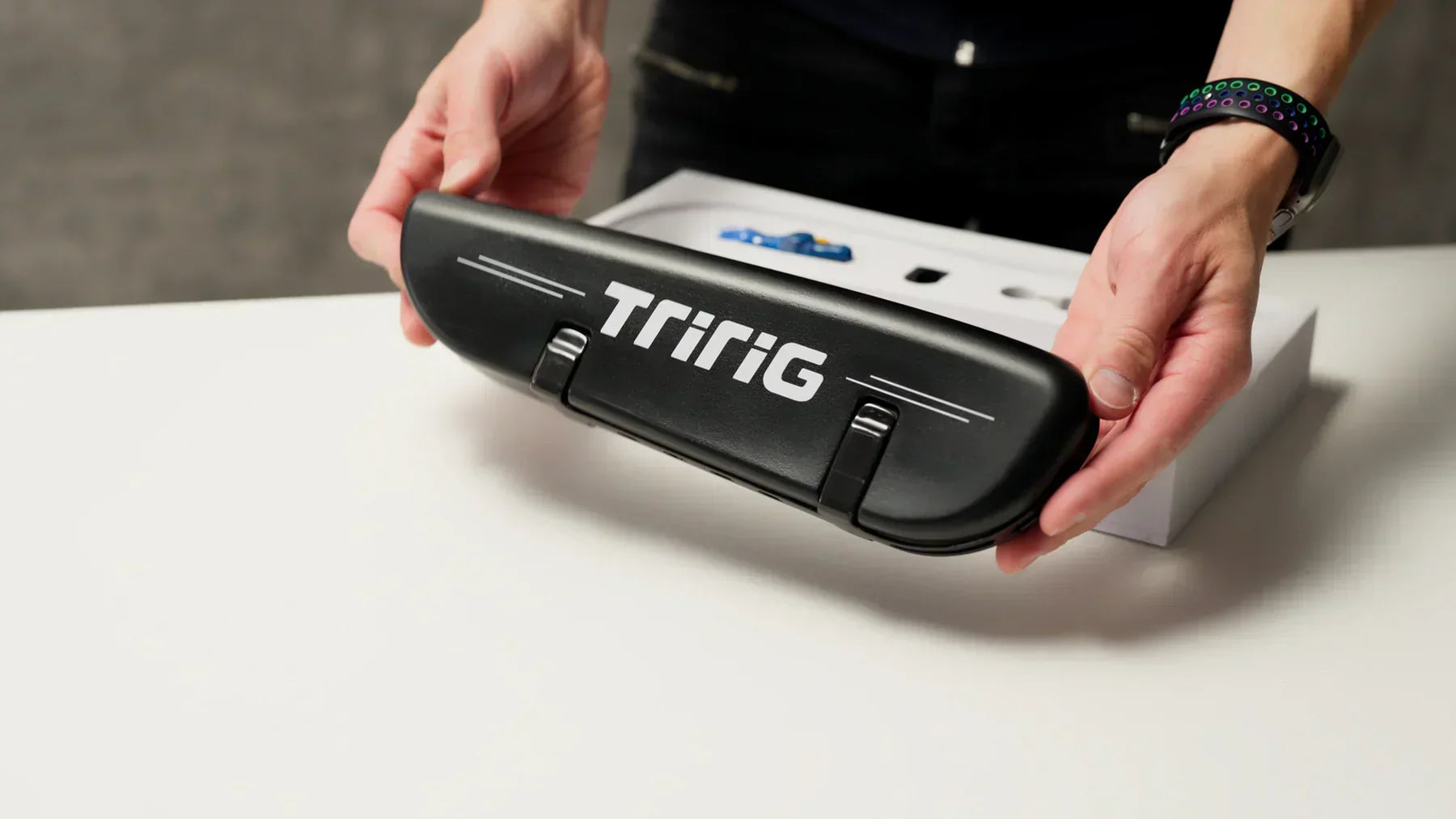 Person holding a black Tririg aerodynamic chainring guard over a white box.