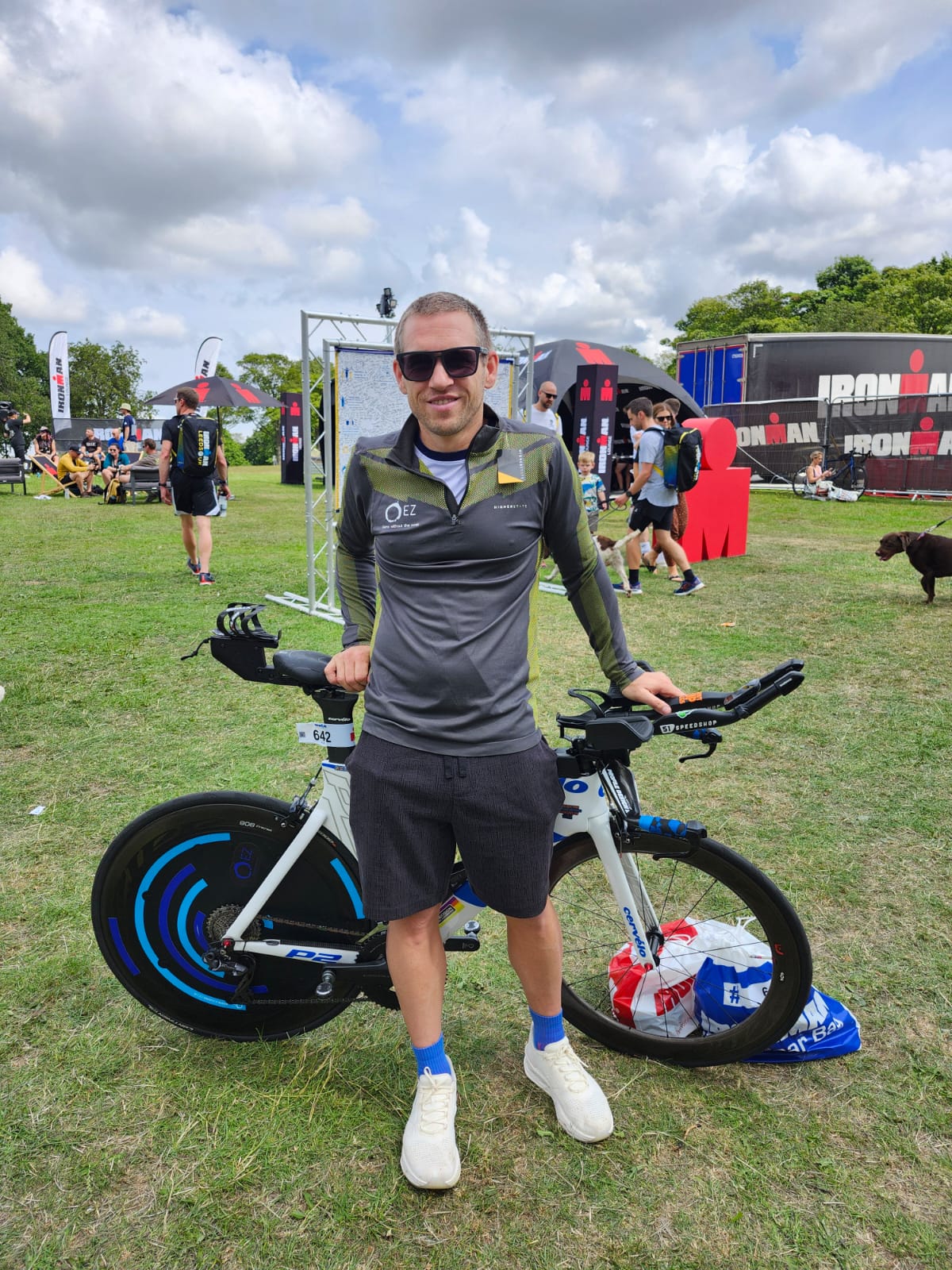 Triathlete standing with a racing bike featuring a blue aerodynamic disc wheel cover.