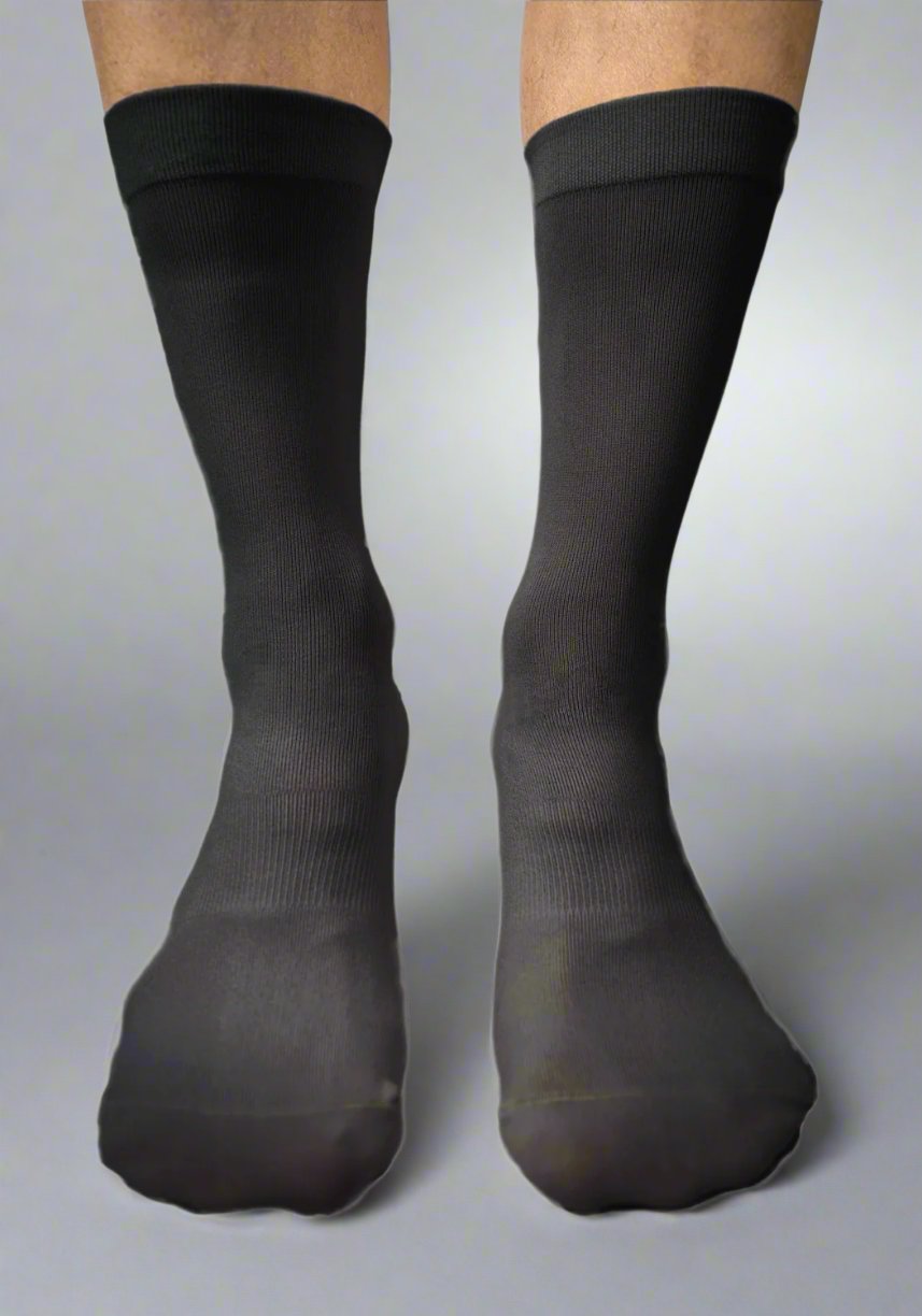 Close-up of person wearing black waterproof cycling socks on a neutral background