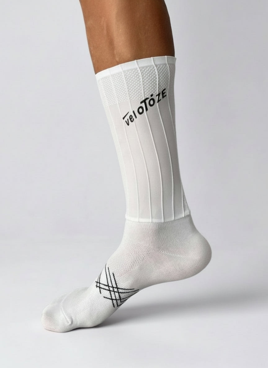 White cycling sock with black veloToze logo, ribbed texture, worn on foot