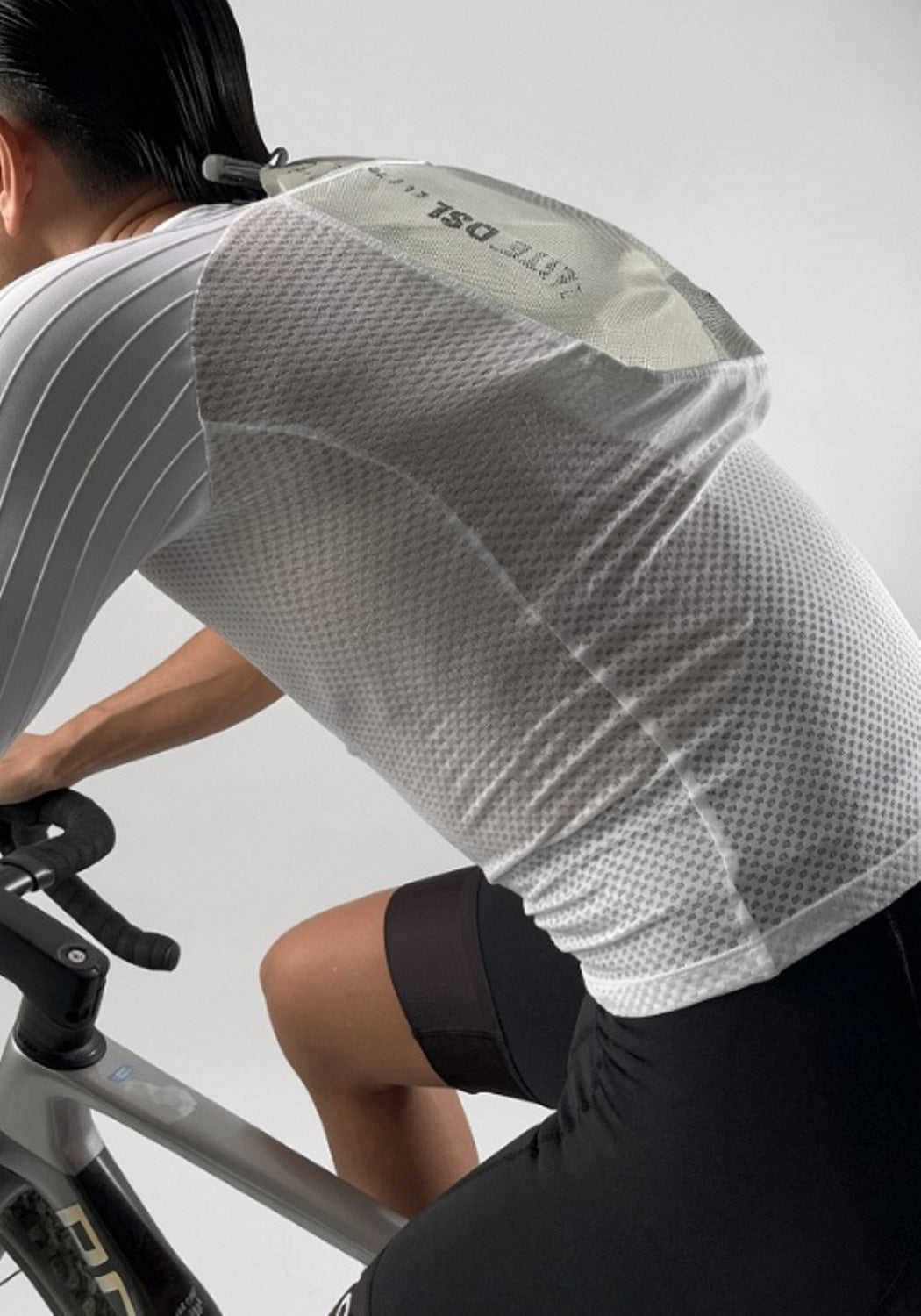 Cyclist in mesh jersey and black shorts riding bike, hydration pack visible on back
