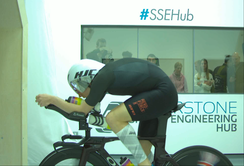 Triathlete in aerodynamic gear training on a time trial bike in a wind tunnel.