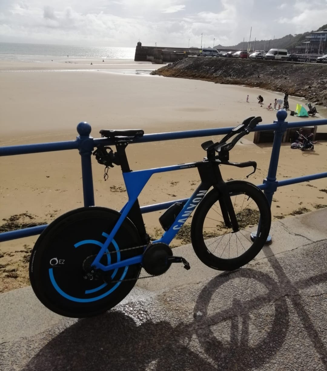 Blue Canyon triathlon bike with aerodynamic disc wheel cover on a beach promenade.