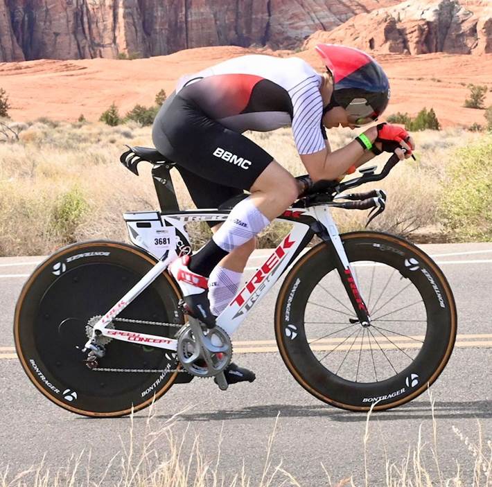 Triathlete riding a Trek aero bike with Bontrager disc wheels on a desert road.