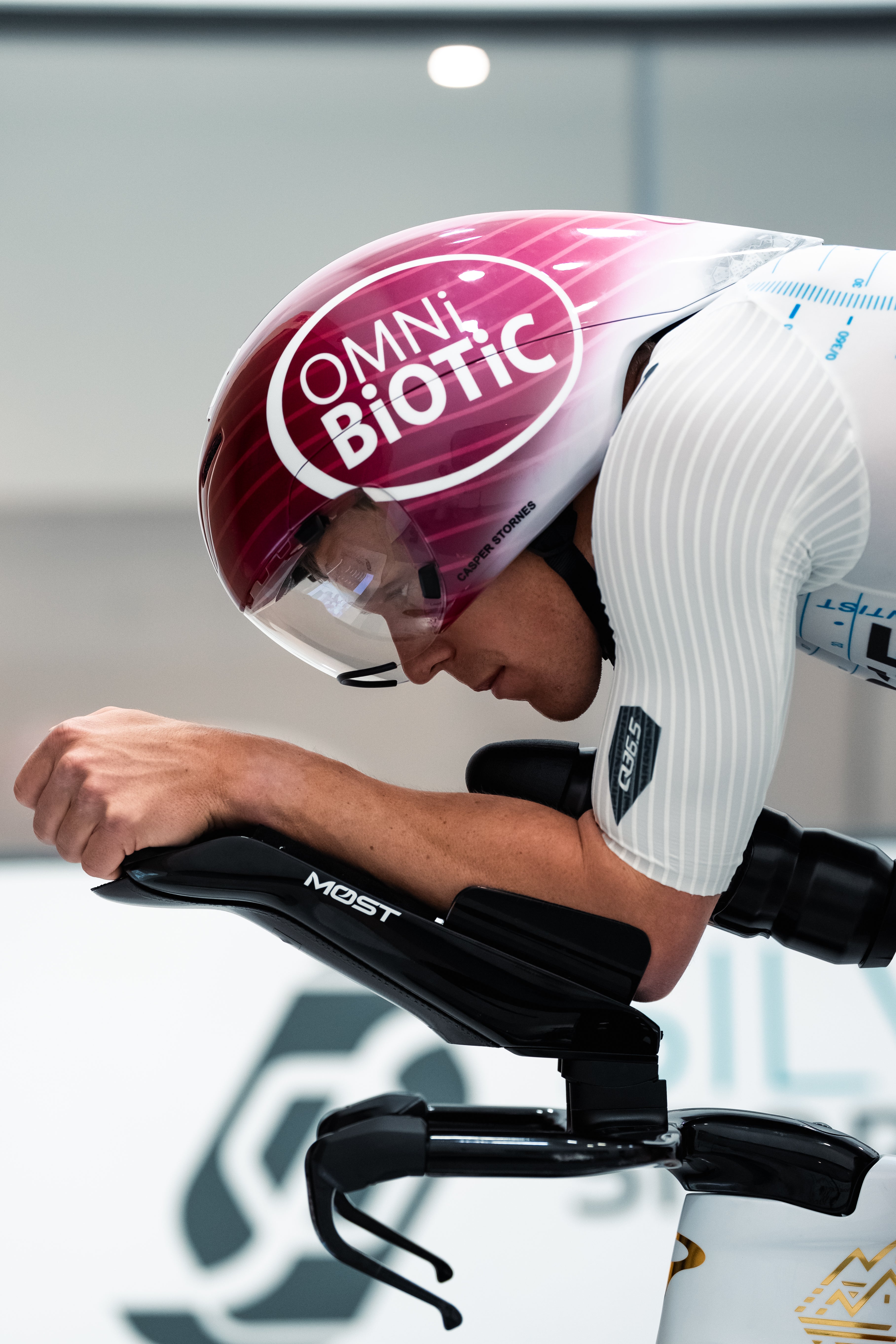 Triathlete wearing an aerodynamic cycling helmet and white jersey on a time trial bike.
