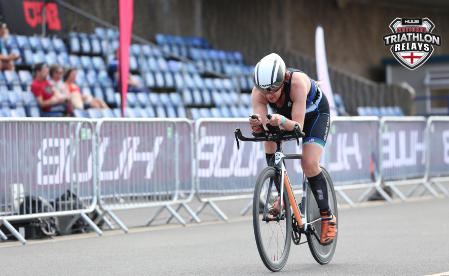 Female triathlete riding a road bike during a triathlon relay race on a paved course.