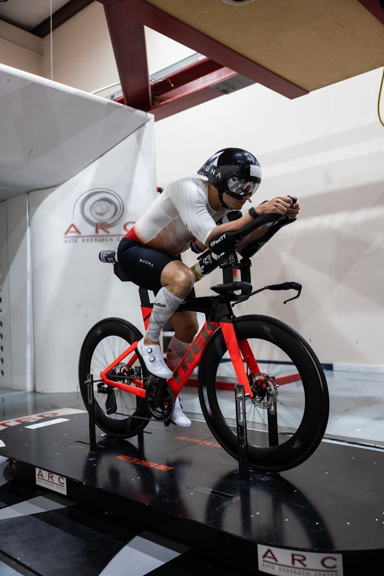 Triathlete training on a stationary bike in a wind tunnel for aerodynamic testing.