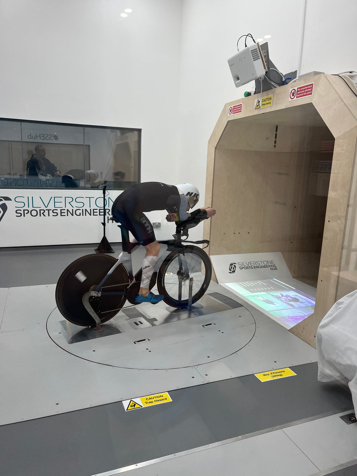 Triathlete in aerodynamic gear performing a wind tunnel test on a racing bike.