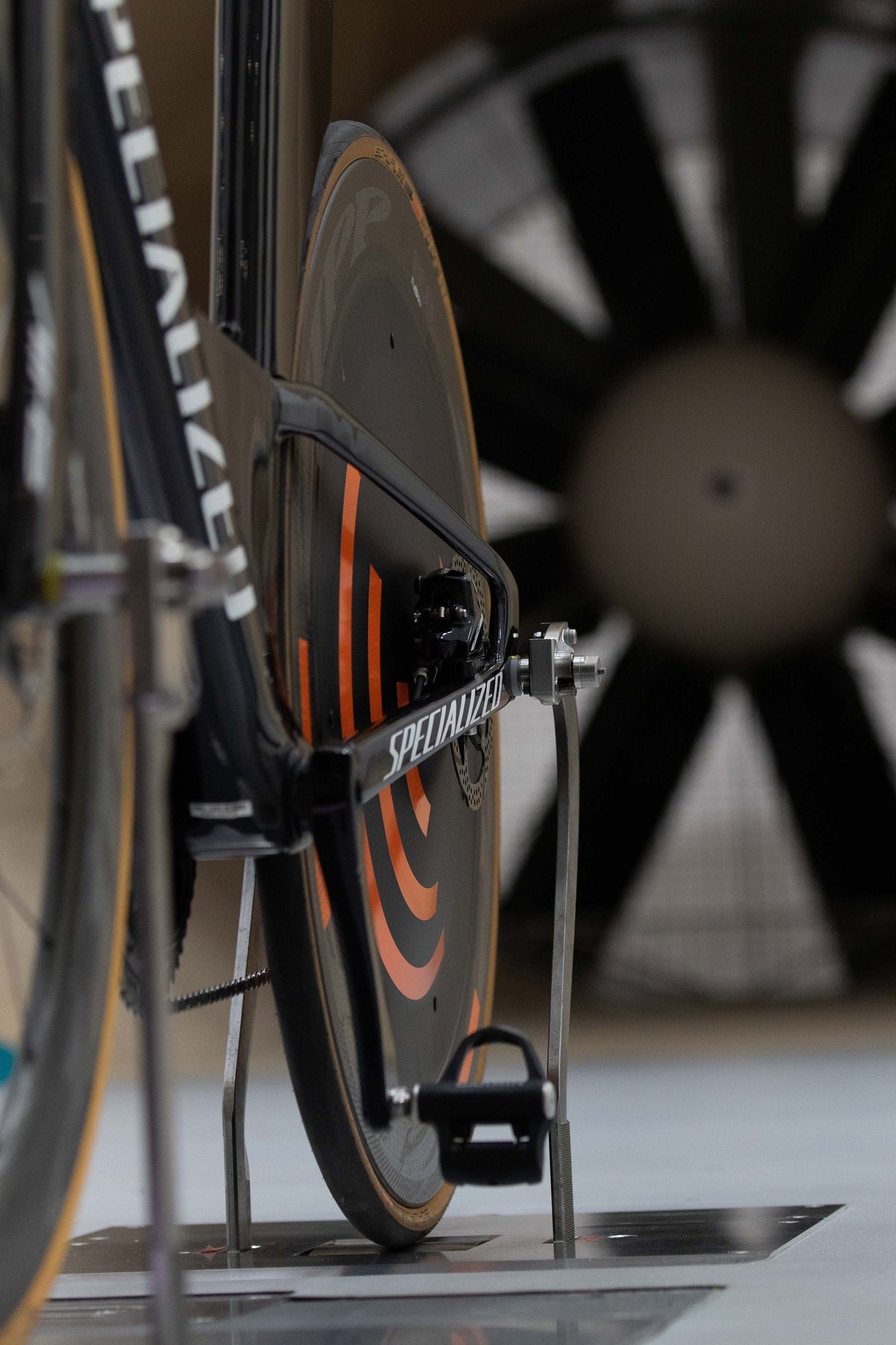 Aerodynamic triathlon bike with a black disc wheel and Specialized frame in a wind tunnel.