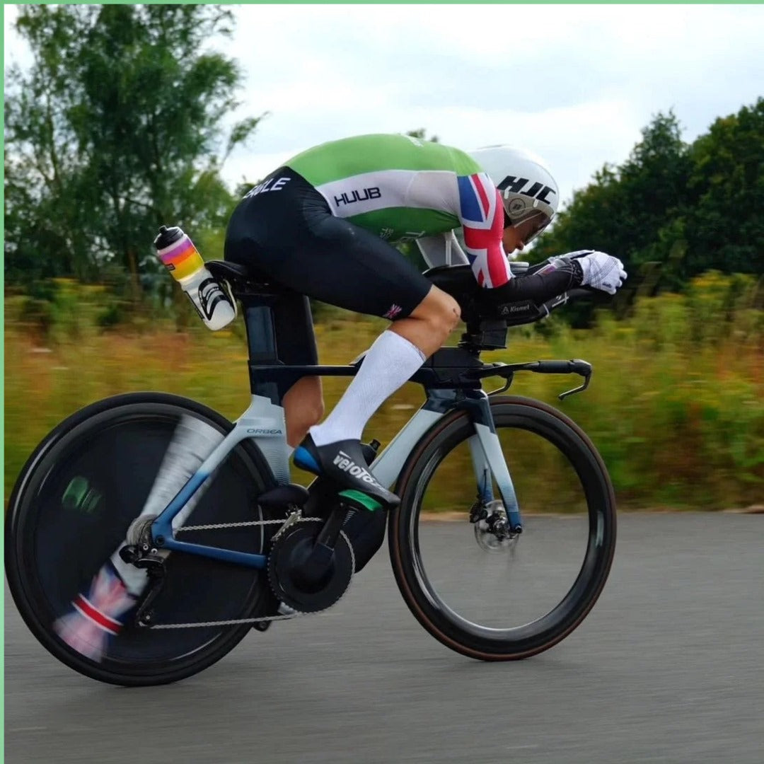 Triathlete riding a high-performance aero bike with a disc rear wheel on a paved road.