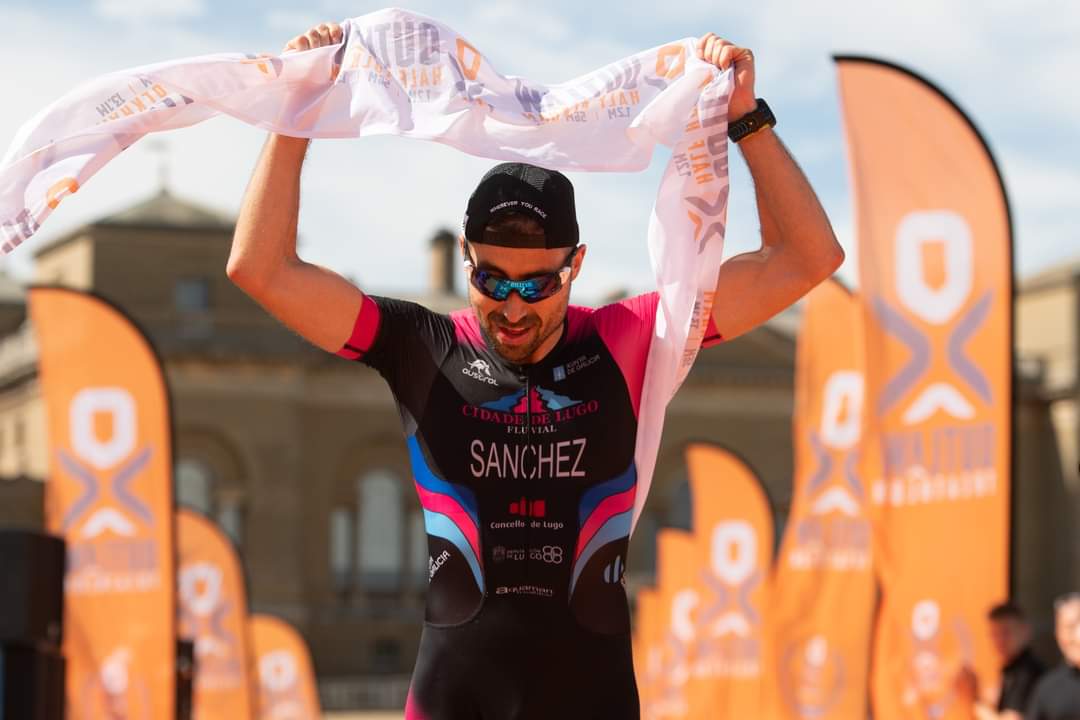 Triathletin in pink-schwarzer Wettkampfkleidung hält ein weißes Handtuch im Zielbereich.