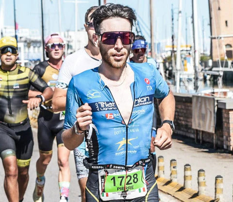 Male triathlete running in a blue racing trisuit during a competition.