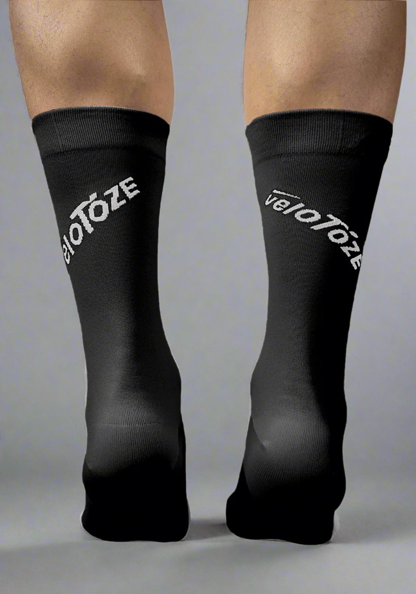 Back view of a person wearing black cycling socks with white veloToze logo