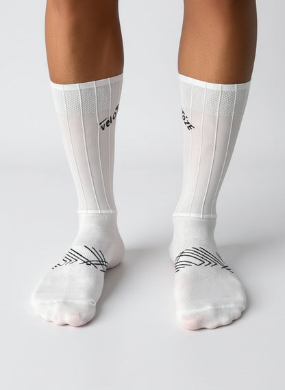 White aerodynamic cycling socks with black geometric design, worn on legs, studio background