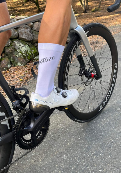 Close-up of cyclist's leg wearing white veloToze sock and S-Phyre cycling shoe on road bike
