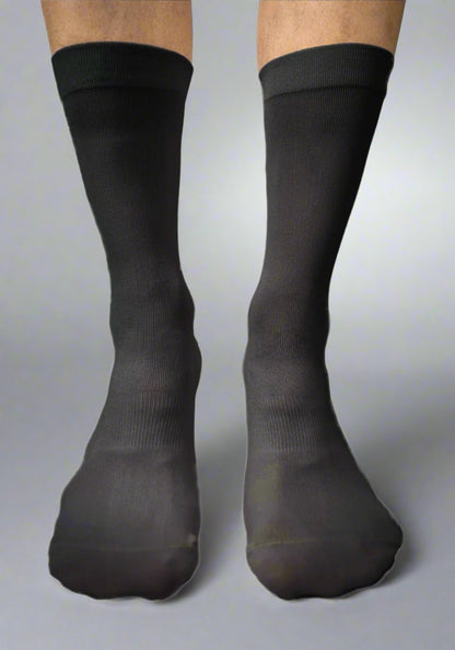 Close-up of person wearing black waterproof cycling socks on a neutral background